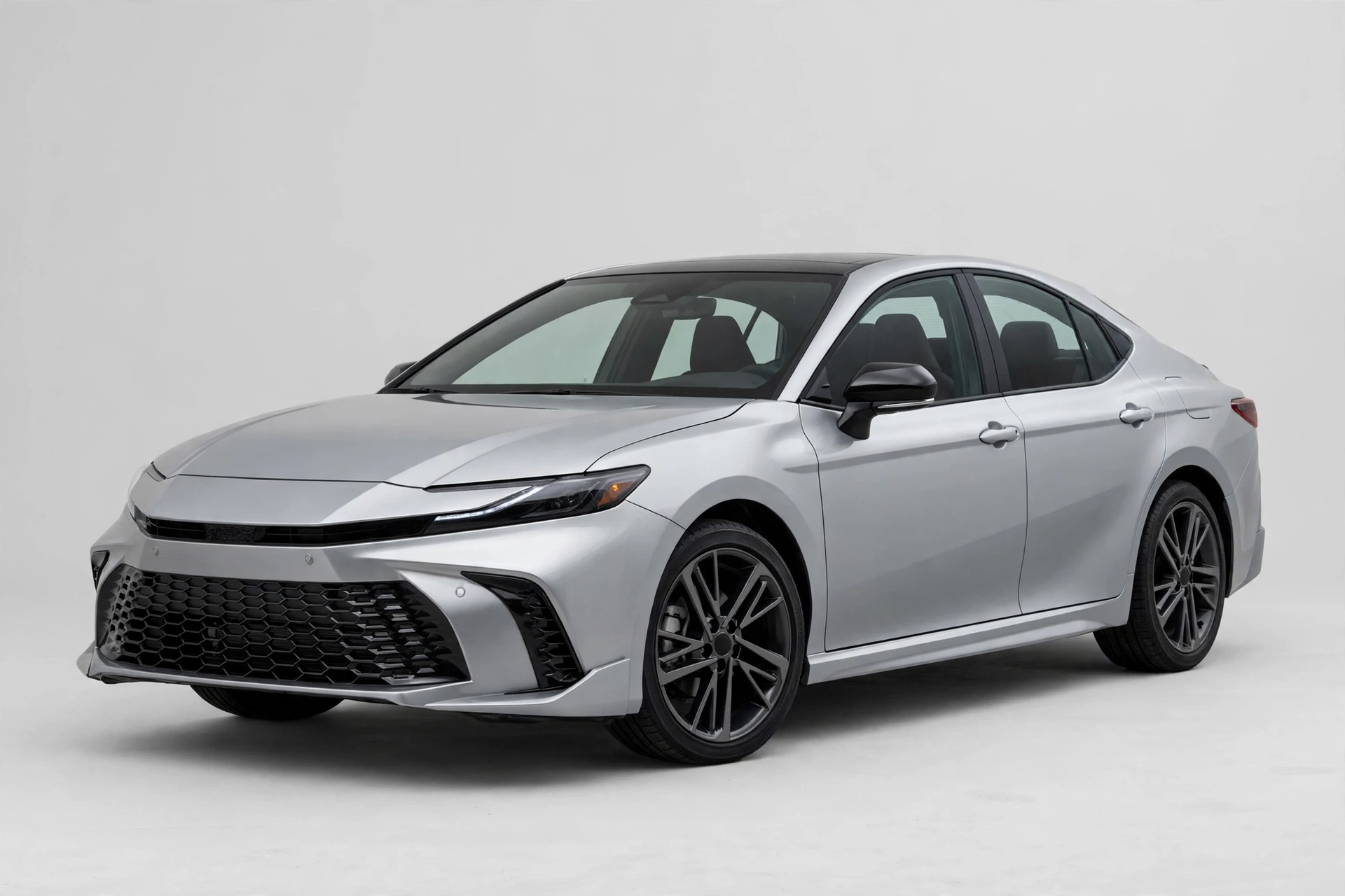 Silver Toyota Camry midsize hybrid sedan in a studio, front three-quarter view